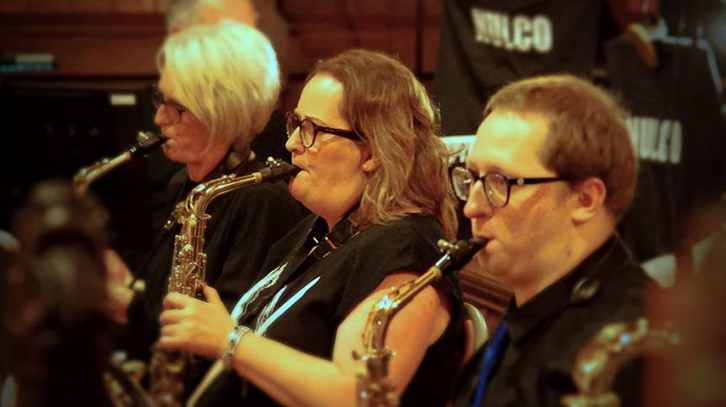 three people sitting down and playing their wind instruments