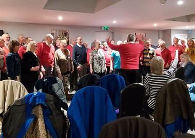 members of the barbershop group standing up and singing in rehearsal