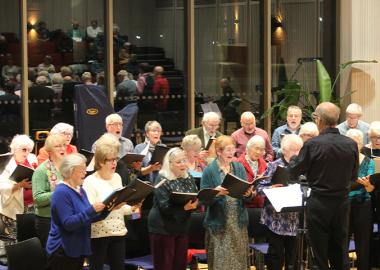 Members of Singing for Pleasure standing up and singing, led by their musical director