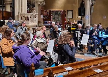 members of the band sit down with their instruments during a workshop