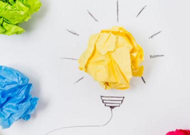 scrunched balls of coloured paper to make up drawing of a light bulb