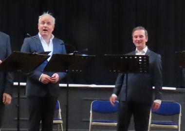 Four singers standing and singing from music in a hall