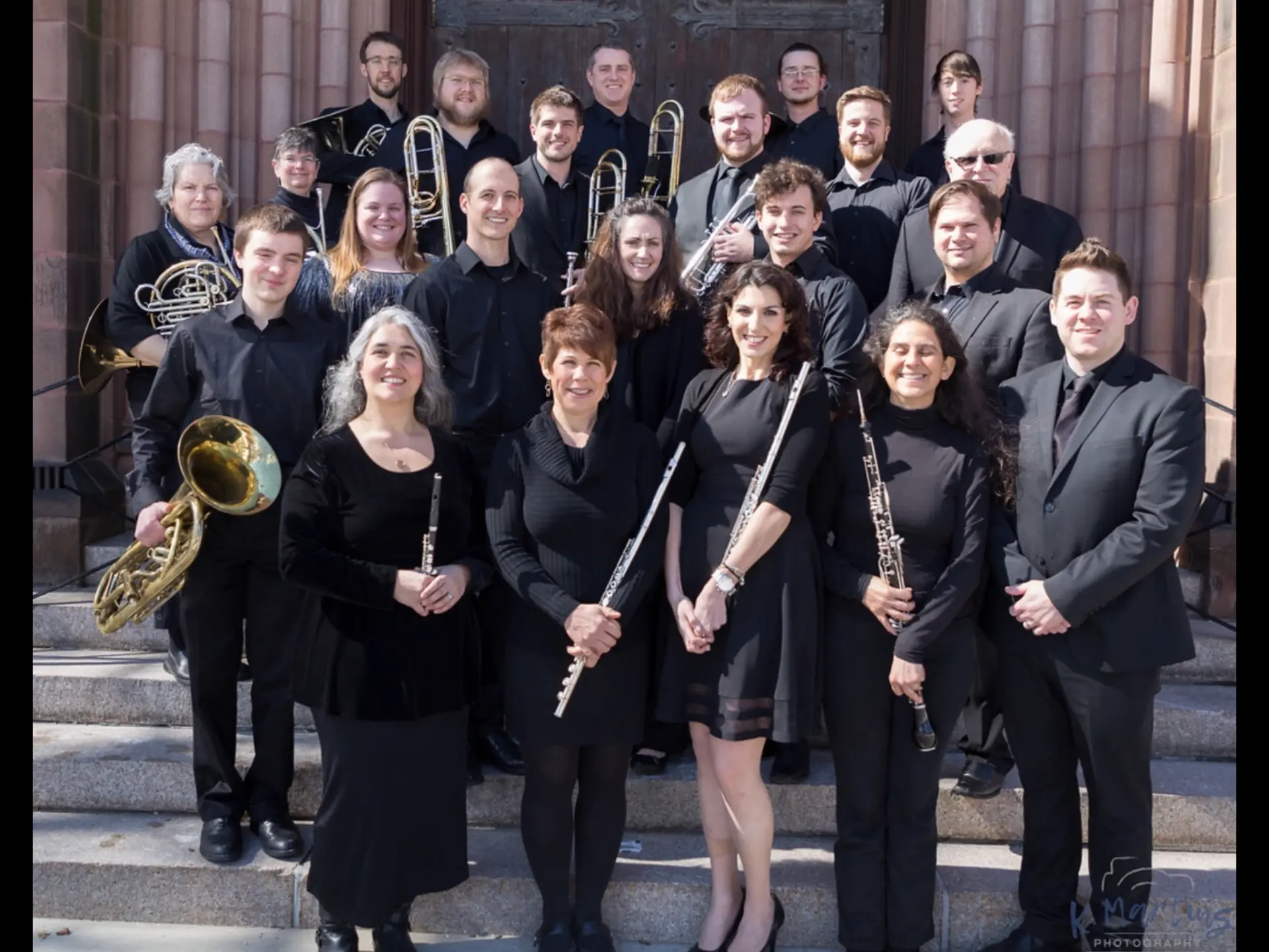 Members of The Valley Winds gathered on the steps of a concert venue